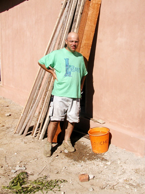 Danilo Barbero beside a building, stacked timber and an orange bucket