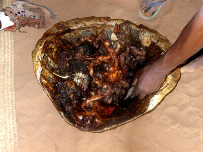 A hand reaching towards food served in a broad tray