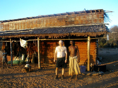 Danilo Barbero and another person outside a thatched wooden building