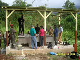 Field team and residents beside a covered community washing facility